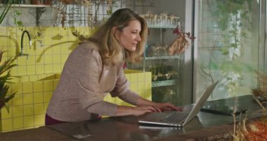Businesswoman using laptop managing online orders. Female small business entrepreneur in front of computer using modern technology browsing internet
