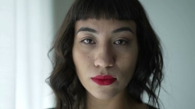 One South American woman with serious expression portrait face wearing red lipstick looking at camera