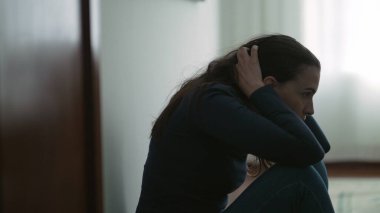 Anxious woman sitting on floor suffering from mental illness at home. Lonely person feeling despair and hopelessness