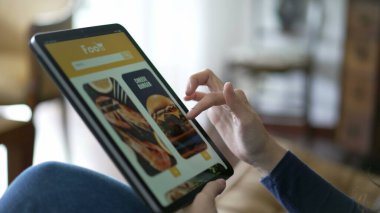 Closeup hand ordering food online holding tablet. Female hands searching for lunch order