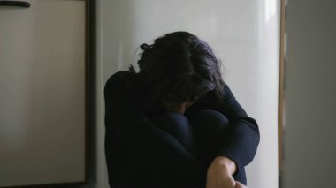 One anxious hispanic latina woman sitting on floor overwhelmed by problems