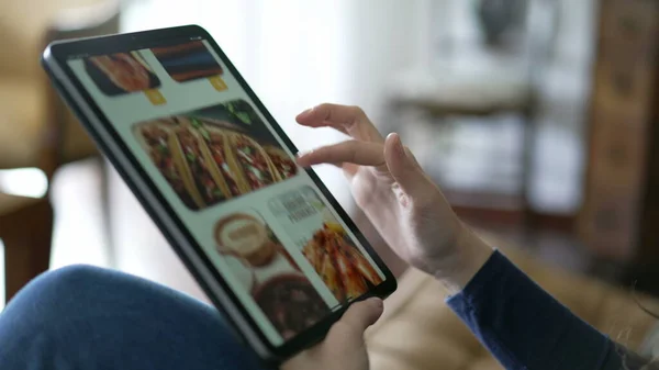 Closeup hand ordering food online holding tablet. Female hands searching for lunch order
