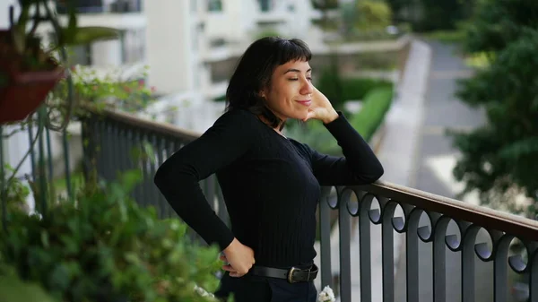 Confident woman standing at home balcony feeling happy. A joyful hispanic south american girl