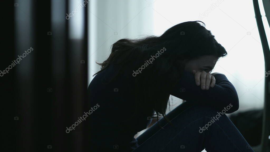 Hopeless person sitting on floor covering face suffering alone. Desperate emotion during hard times. Girl feeling lonely
