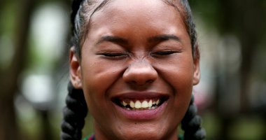 Mixed race black girl laughing outdoors looking at camera
