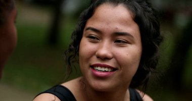 Hispanic young woman laughing with friend outside