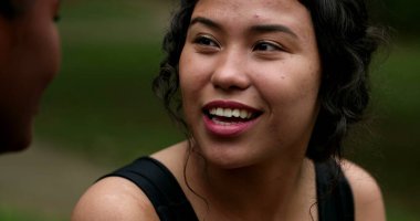 Hispanic young woman laughing with friend outside
