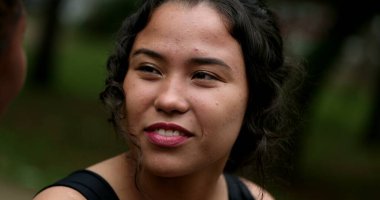 Hispanic young woman laughing with friend outside