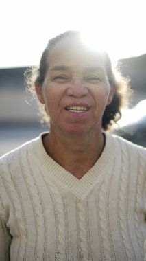 Portrait of a south american older woman in 70s standing outside. Smiling happy senior mature person
