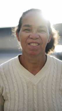Portrait of a south american older woman in 70s standing outside. Smiling happy senior mature person