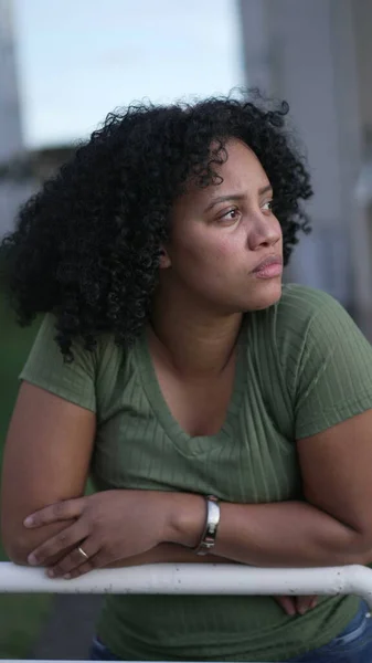 A pensive Brazilian black woman standing outside thinking. A young hispanic black girl