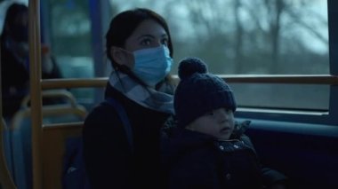 Mother riding bus with baby infant on lap during covid-19 face mask