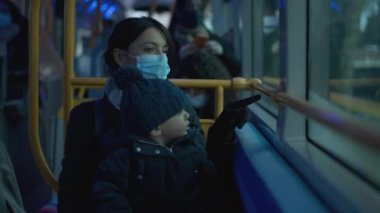 Parent and child riding bus during pandemic wearing covid-19 face mask