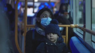 Parent and child riding bus during pandemic wearing covid-19 face mask