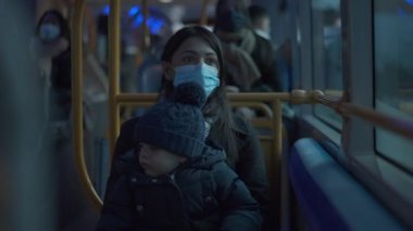 Mother riding bus with baby infant on lap during covid-19 face mask