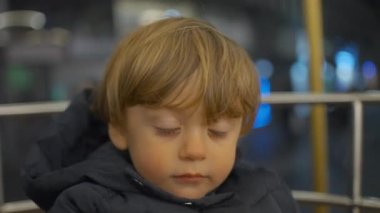 Child boy waiting for carousel to start sitting patiently
