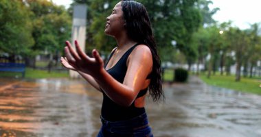 Woman standing outside in pouring rains hower, happiness concept