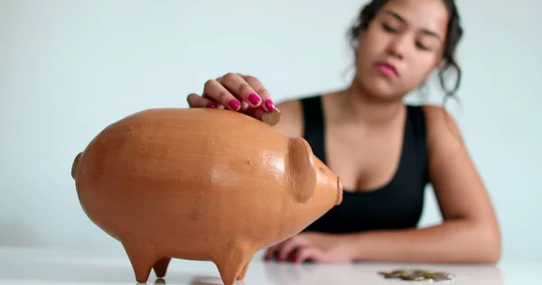 Woman hand putting coins into piggy bank. Person saving money