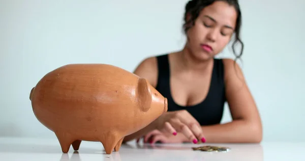 Woman hand putting coins into piggy bank. Person saving money