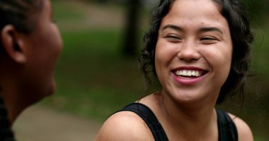 Two friends real life laugh and smile together outdoors