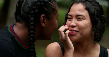 Two friends laughing and smiling outside. Interracial friendship, hispanic and african women