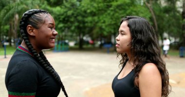 Two friends in conversation outdoors. Interracial friendship, African and hispanic latin girlfriends