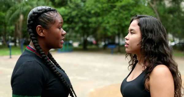 Two friends in conversation outdoors. Interracial friendship, African and hispanic latin girlfriends