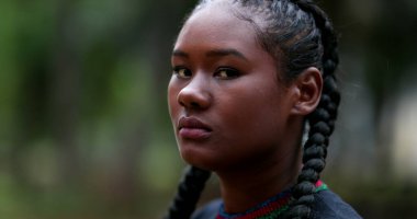 Dışarıdaki kameraya bakan genç, ciddi bir zenci kadın. Dramatik Afrikalı kız seyirciye bakıyor