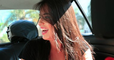 Candid authentic laugh of girl in the back seat of a car smiling Joyful woman real life laugh while riding taxi cab