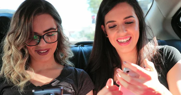 Candid Friends Holding Cellphones Back Seat Taxi Authentic Girlfriends Looking — Stockfoto