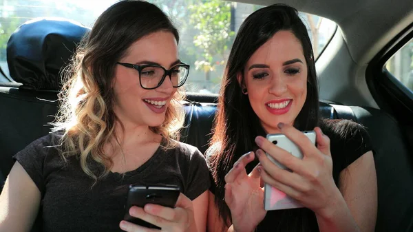 Girls looking at cellphone in the back seat of a car