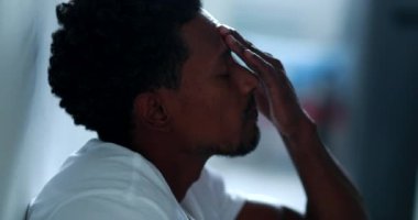 Concerned black man rubbing face and head with hand feeling worry and stress