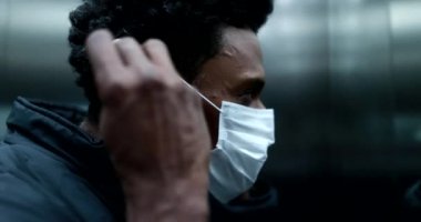 Black african man putting on covid mask inside elevator and stepping outside