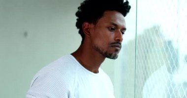 Pensive African American man at home looking out window. Thoughtful black person thinking