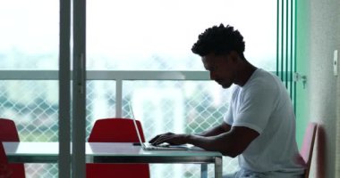Candid African American working from home apartment in front of laptop