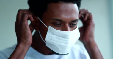 African american wearing and adjusting mask against coronavirus