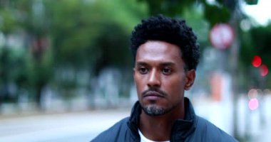 Pensive man walking in city, thoughtful black african american walks in urban sidewalk
