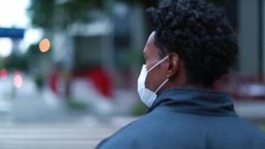 Suspicious black African man wearing covid-19 surgical pollution mask in city downtown