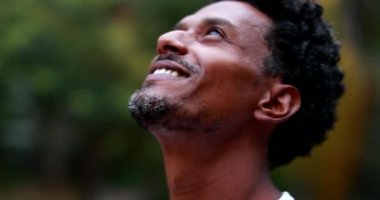 Positive african american man feeling hope and faith looking up