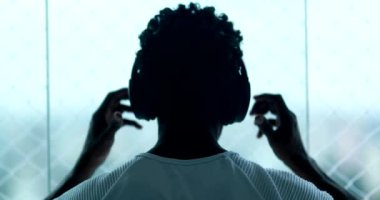Back of black guy listening to song, man removes headphone and music stops