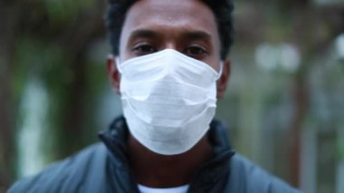 Portrait of black african man wearing surgical mask epidemic prevention outside, person looking to camera with covid mask