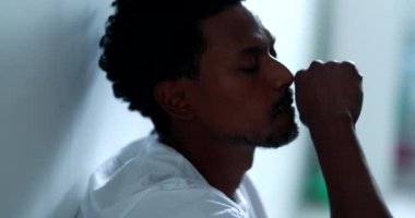 Worried black man feeling distraught and preoccupied sitting on home floor, suffering african american person