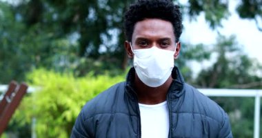 Portrait of black african man walking towards camera wearing covid mask