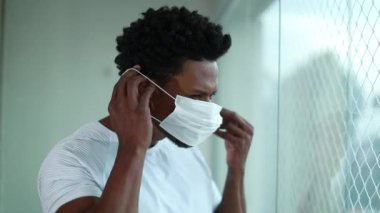 African man putting covid mask. Black man puts surgical mask against epidemic outbreak disease prevention
