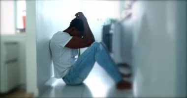 Pensive man sitting on kitchen floor feeling preoccupied thinking
