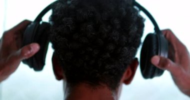 Back of person putting on headphones, man wearing noise cancelling headphones