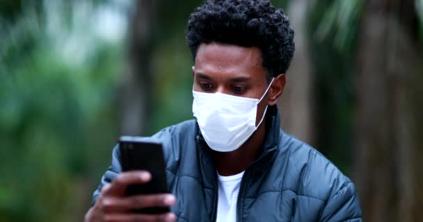 Black African Man Checking Cellphone Wearing Covid Mask Outdoors — ストック動画