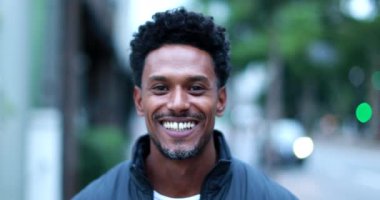 Handsome confident African person walking forward in city smiling portrait