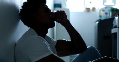 Worried African american man sitting on home floor feeling despair, frustration, suffering from mental illness