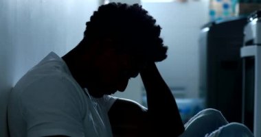 Man feeling emotional pain sitting on kitchen floor feeling desperate and depression